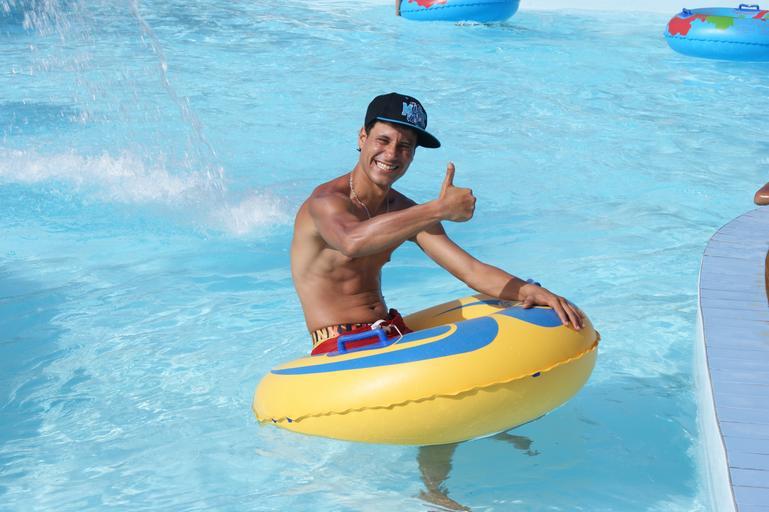 mladý muž s kšiltovkou v bazénu a s nafukovacím kruhem